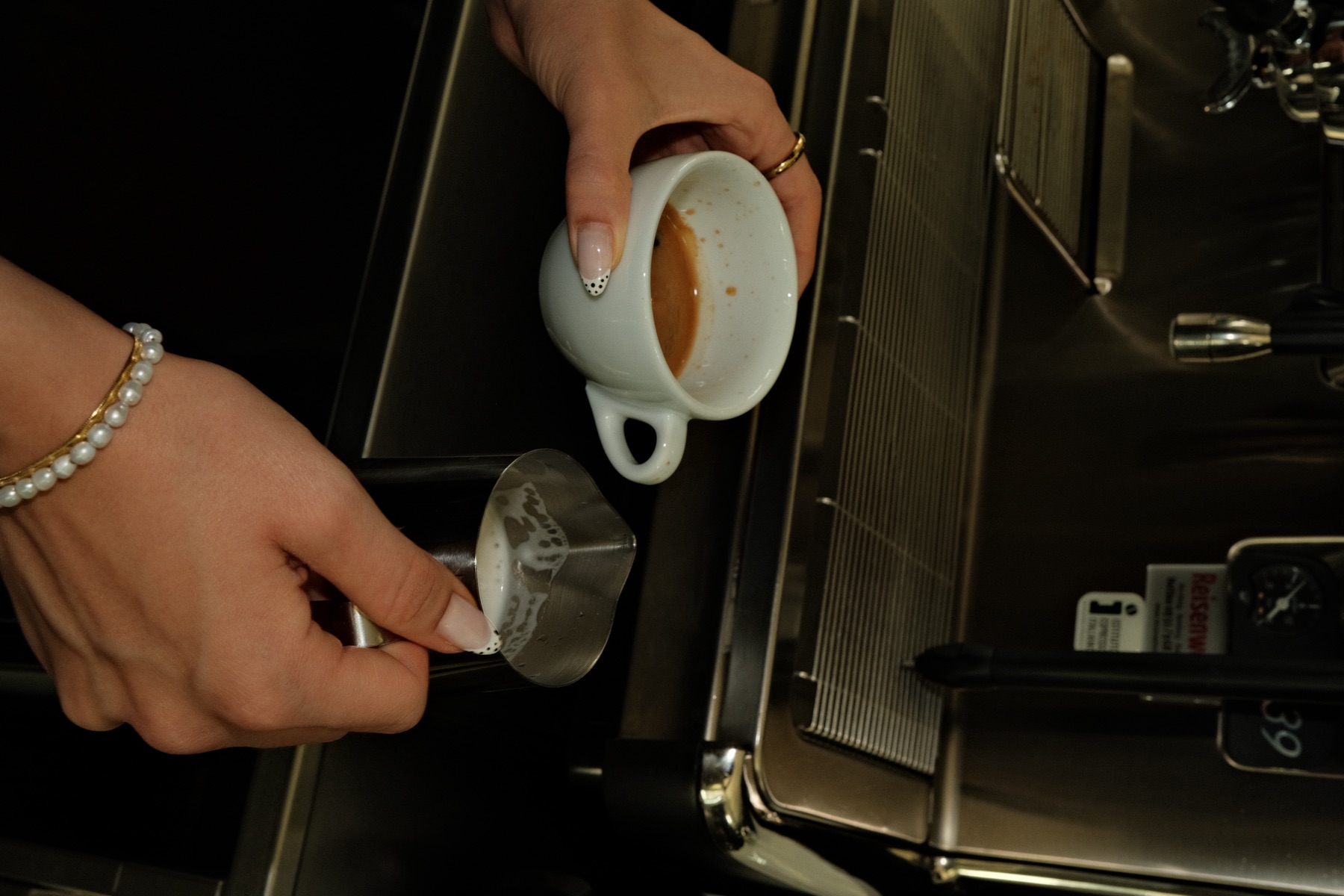Barista gießt Milch in den Kaffee